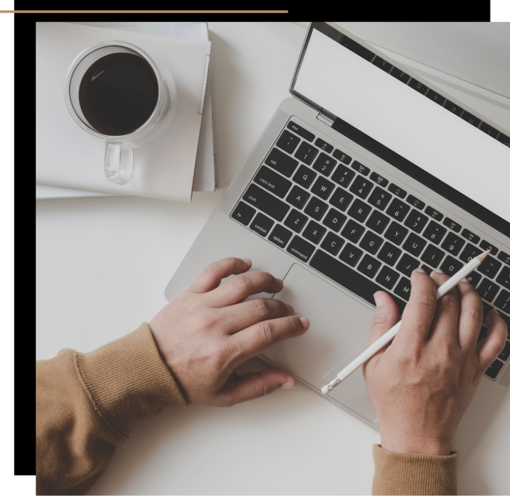 Person using a laptop with a pencil and cup of coffee