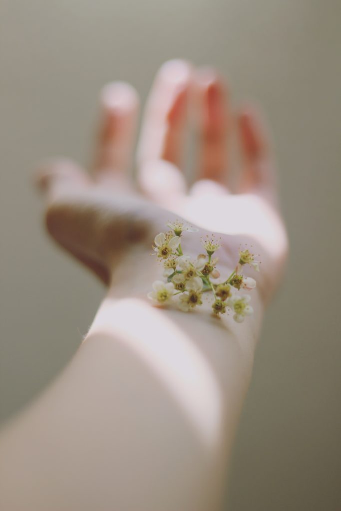 A woman's arm with a sprig of elderflower positioned on the wrist 