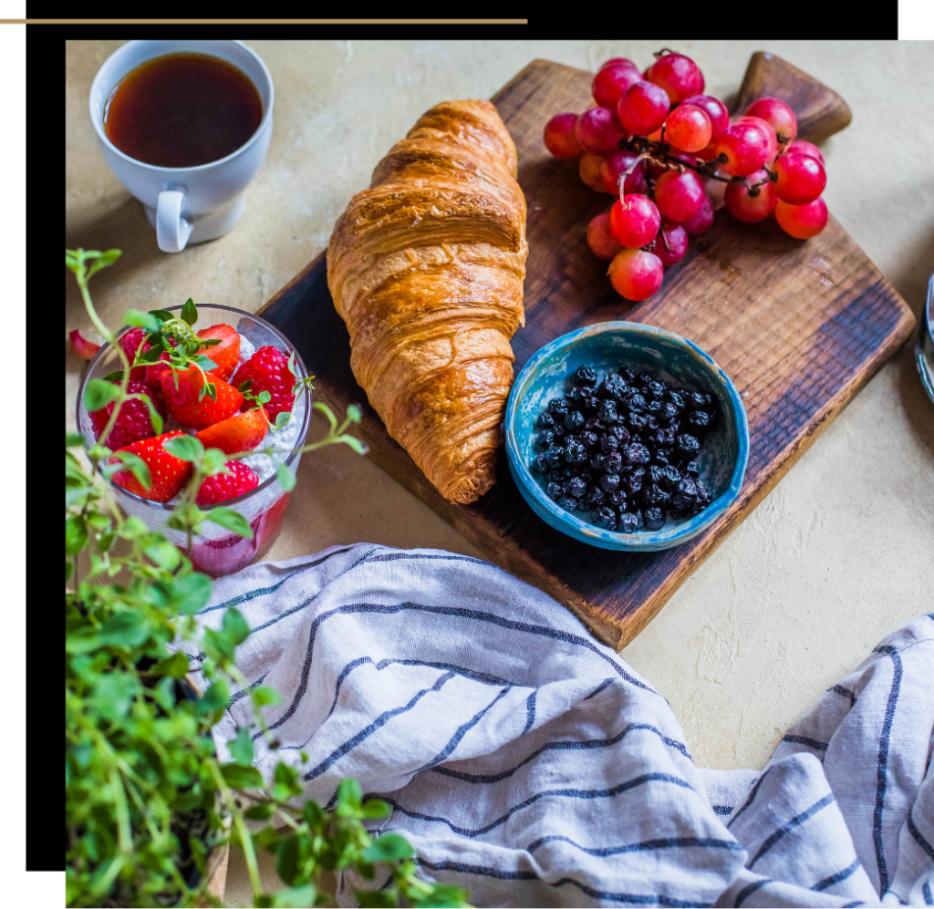 A platter with a croissant, raisins and grapes 