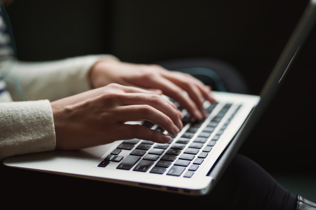 A person typing on a silver and black laptop 