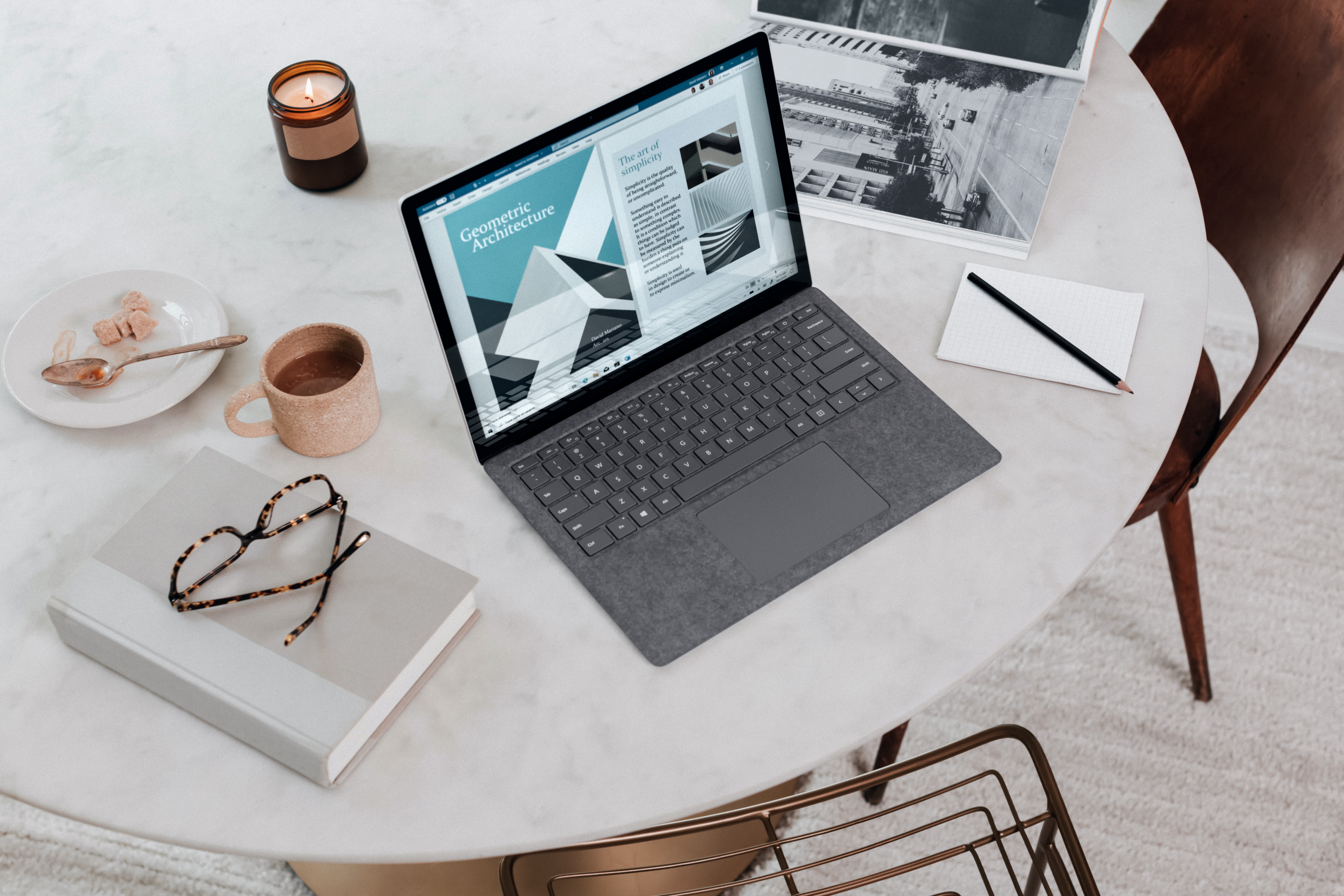 laptop on table with pens and coffee and a candle