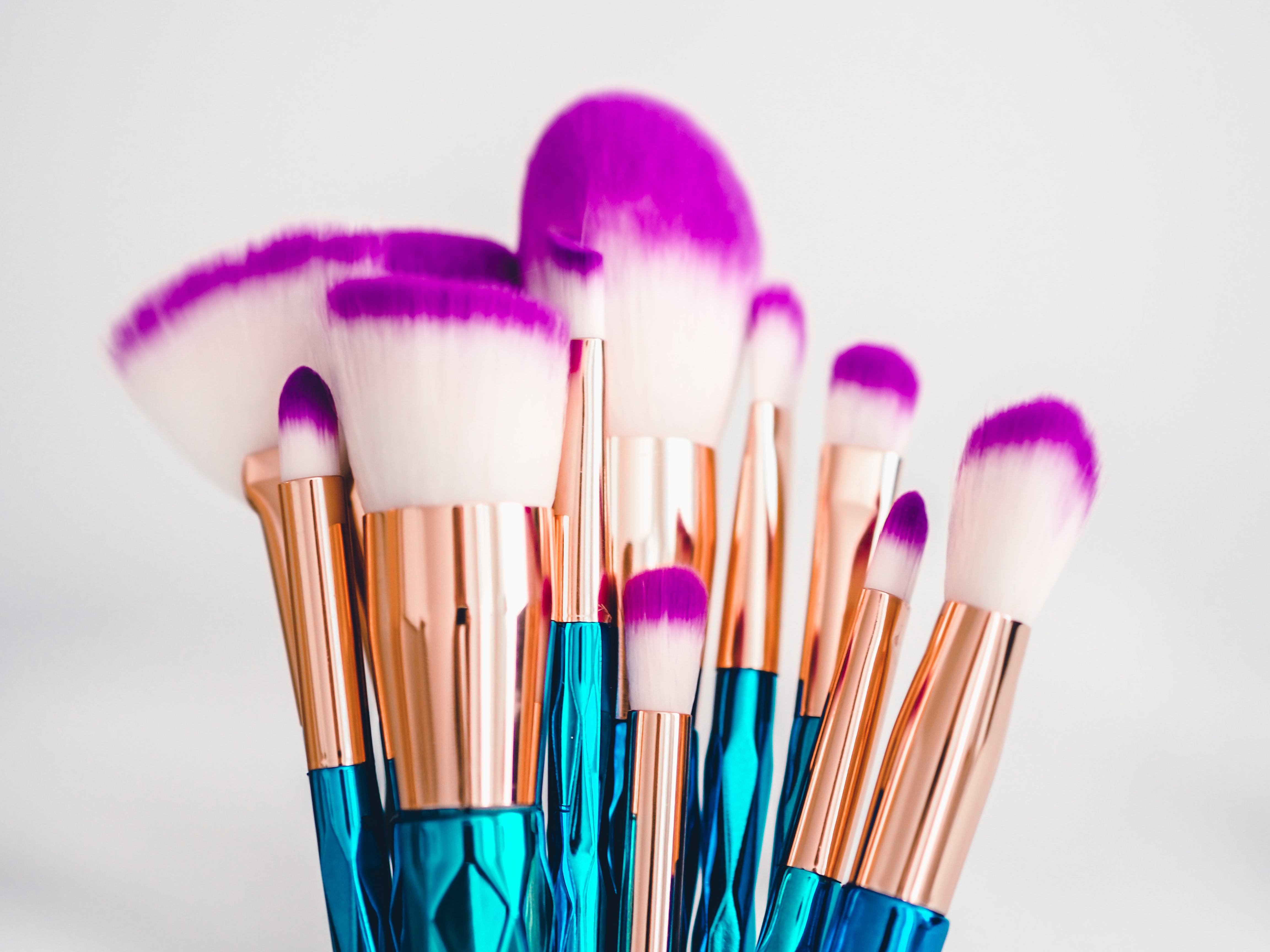 Makeup brushes with turquoise and gold handles and purple tips