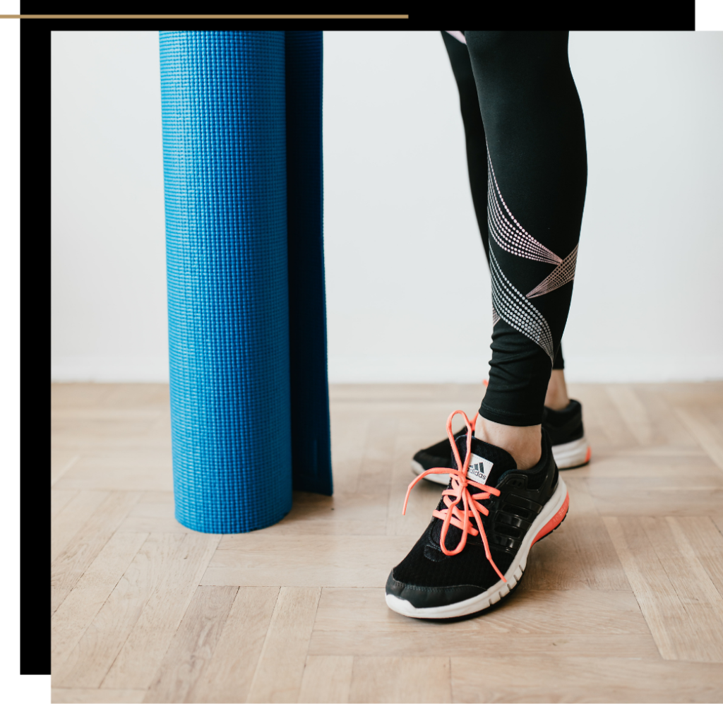 A woman in leggings and trainers with a blue workout matt