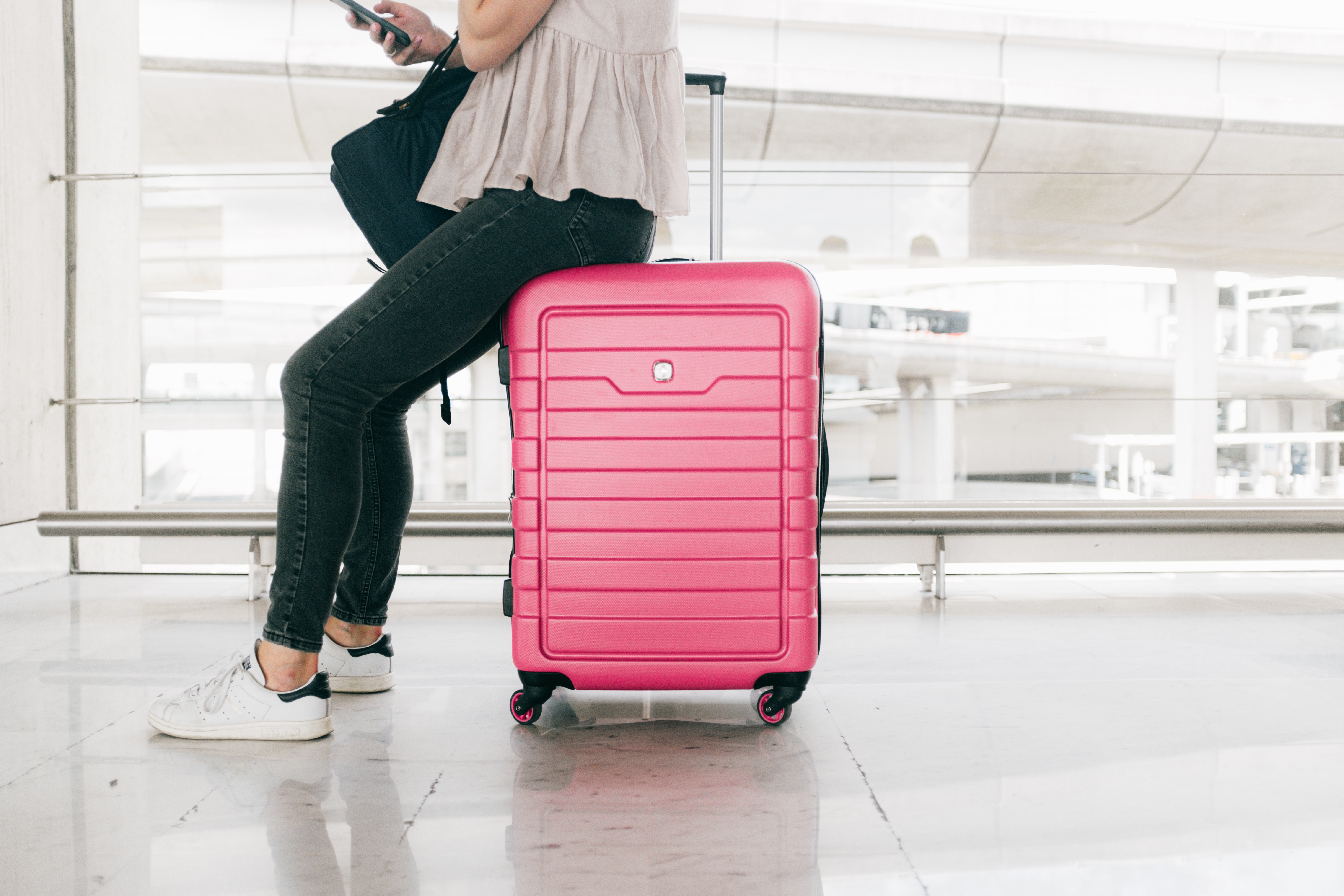 A woman sitting on a pink suitcase